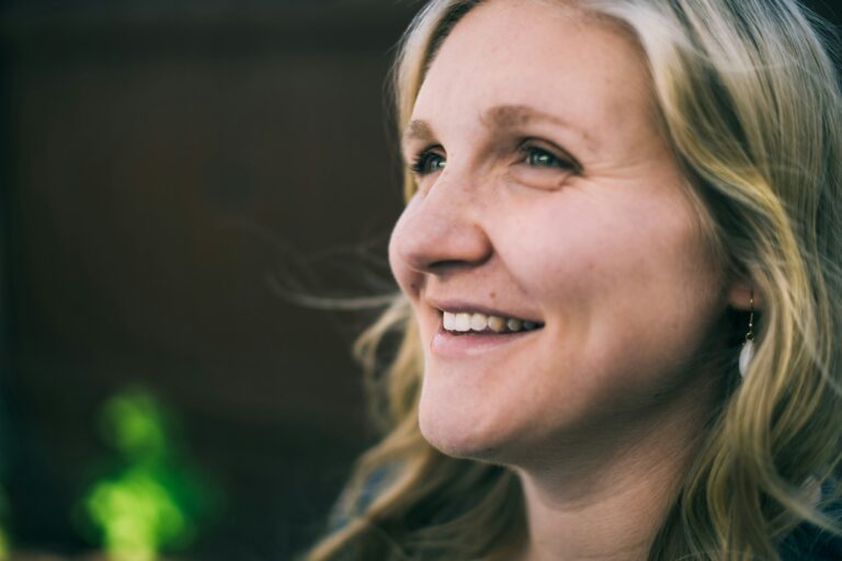 Close-up of a smiling blonde woman highlighting the natural appearance of the eyes and surrounding facial features.